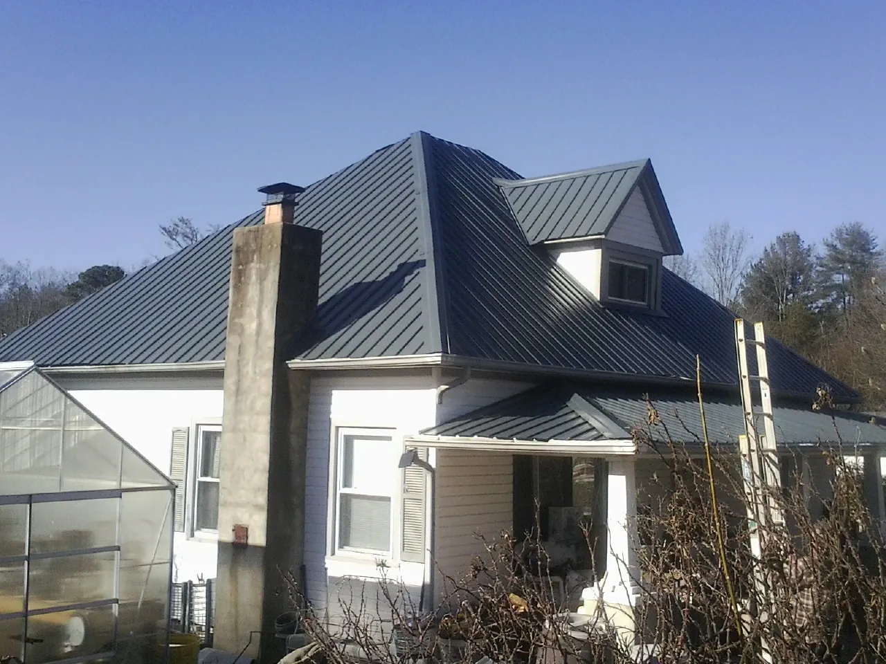 Dark blue standing seam metal roof on a white farmhouse with dormer — Slate & Tile Roof Repair by Roofing Brothers in Otoe