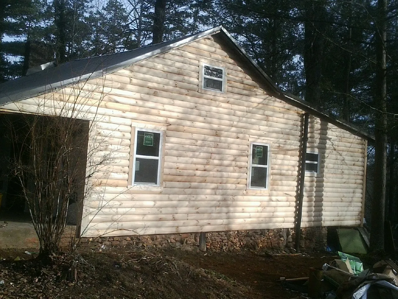 New log siding and dark metal roofing on a gable end in Otoe