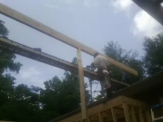 Carpenter setting a ridge beam over a new addition frame — Ice Dam Removal by Roofing Brothers in Otoe