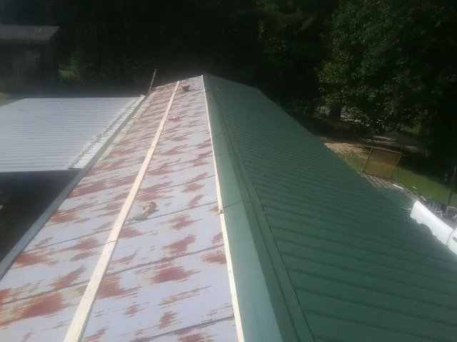 Old rusted panels beside newly installed green metal roofing — Wind Damage Roof Repair by Roofing Brothers in Otoe
