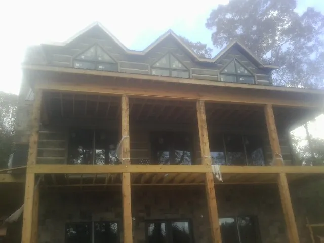 Dormers and porch framing on a large log home under construction — Roof Coating work by our crew in Otoe
