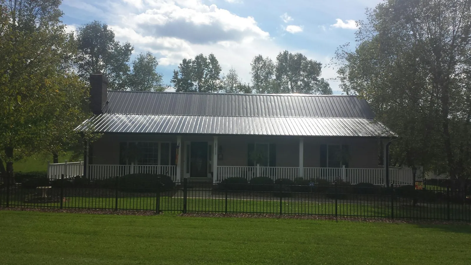 Gray metal roof on a brick ranch with a full width front porch — Gutter Guard Installation work by our crew in Otoe