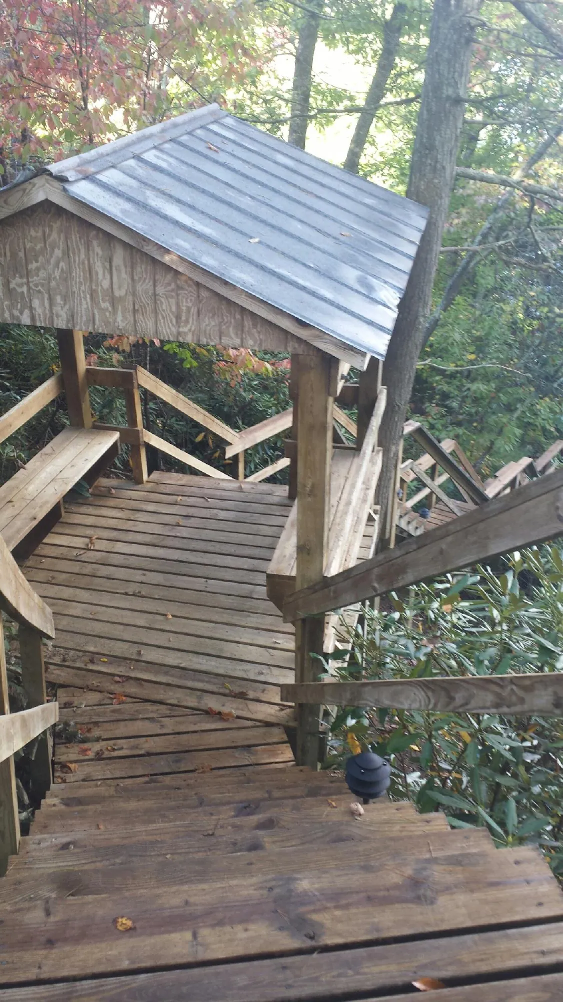 Metal roofed shelter over wooden steps on a wooded walkway — Skylight Repair & Installation work by our crew in Otoe