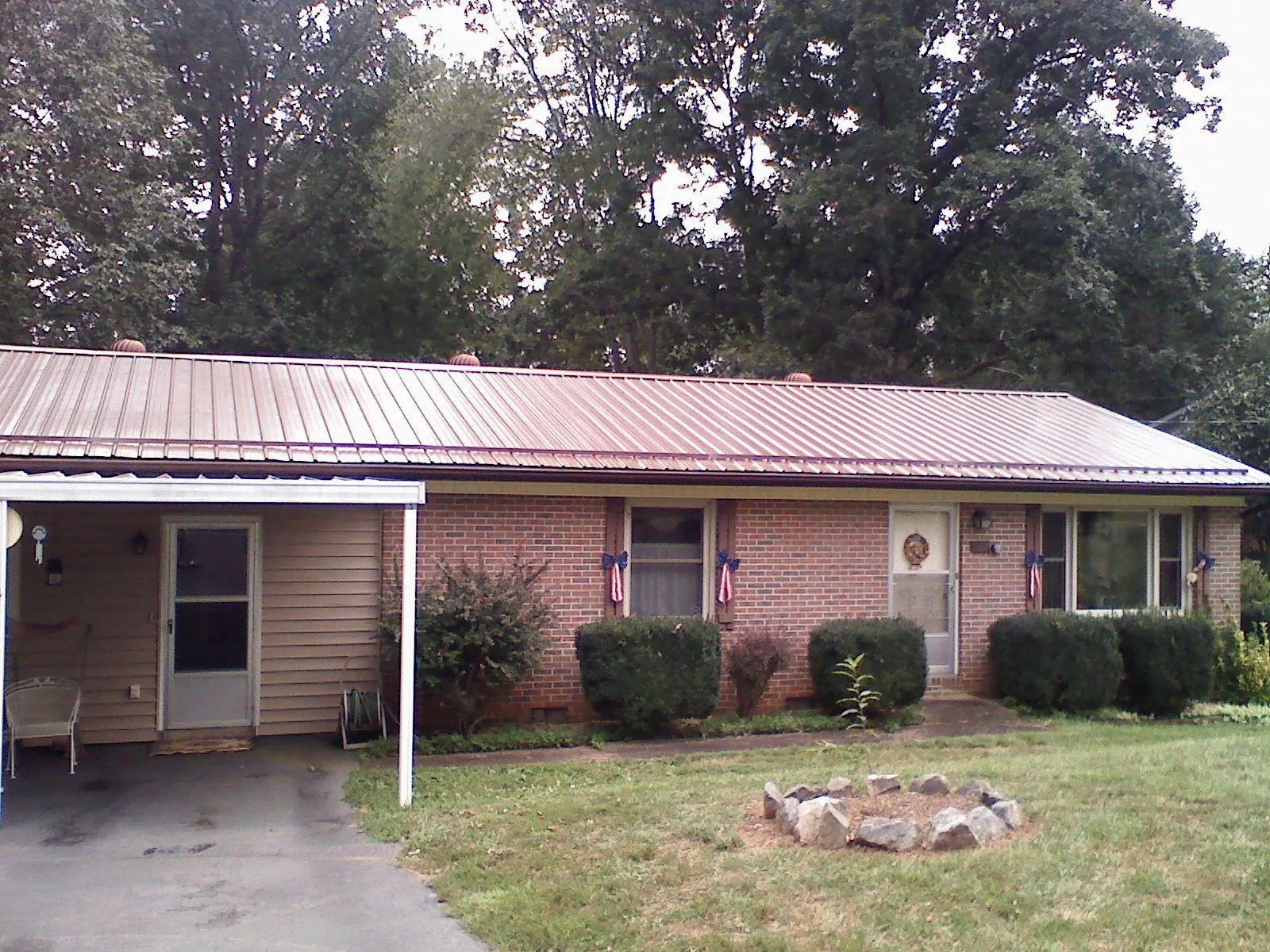 Bronze metal roof and carport on a brick ranch home — Roof Repair work by our crew in Otoe