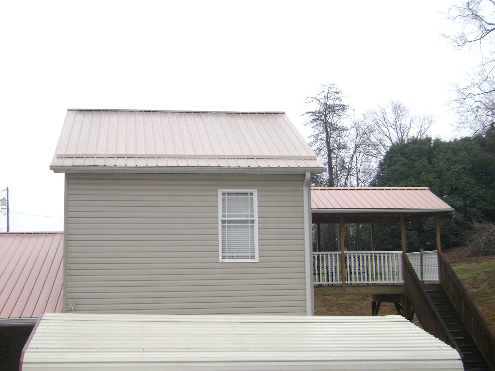 Tan metal roofs on a two story addition and attached porch, from a Roof Replacement job in Otoe