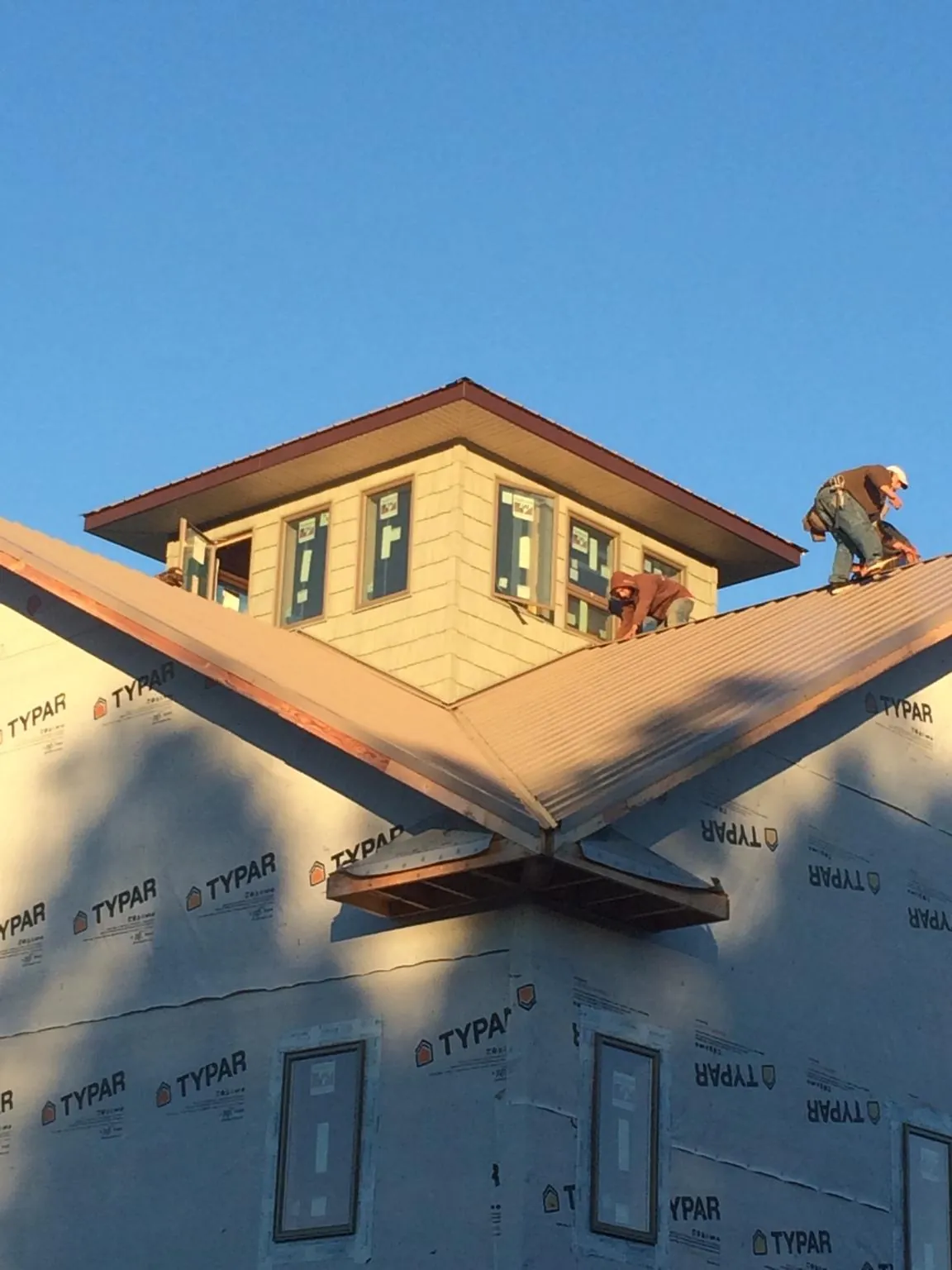 Roofers working around a rooftop cupola on a new metal roof at sunset — Roof Waterproofing in Otoe by Roofing Brothers